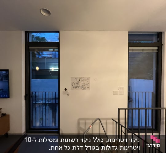 חדר עם חלונות גדולים, טלוויזיה ומעקה מדרגות